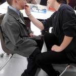 Ninth-grader Georgia Clark, who served as assistant director for &ldquo;Annie,&rdquo; paints a beard on Fischer Cain, a fifth-grader who played Lt. Ward. &ldquo;He started using a police hold on Lily and Rooster from Day One,&rdquo; laughs teacher Heather Johnson. &ldquo;We&rsquo;ve found this calling.&rdquo; (Photo by Kat Bryant | The Daily World)