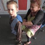North River teacher Karen Furth helps kindergartner Joey Denton with his microphone. (Photo by Kat Bryant | The Daily World)