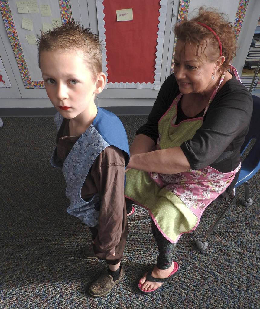 North River teacher Karen Furth helps kindergartner Joey Denton with his microphone. (Photo by Kat Bryant | The Daily World)