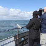 Jay Evans scans the water with binoculars, flanked by his daughter, Elise (left), and his wife, Laura. The family had traveled from Woodinville for the whale-watching tour. (Kat Bryant | The Daily World)