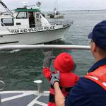 Ed Welter waves from the Fish and Wildlife Police boat to CWO Cheston Evans and his young stepson, Aiden. (Photo by Kat Bryant | The Daily World)