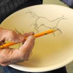 Photos by Kat Bryant | The Daily World                                 North Beach Artists Guild member Ardith Forsgren draws a horse design to be painted onto a bowl.