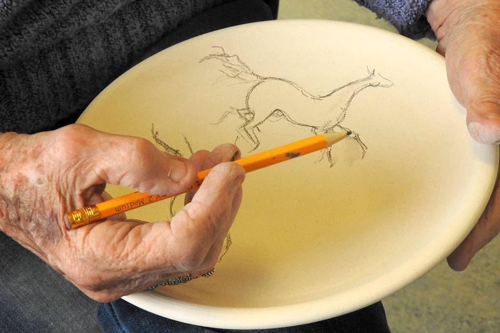 Photos by Kat Bryant | The Daily World                                 North Beach Artists Guild member Ardith Forsgren draws a horse design to be painted onto a bowl.