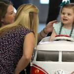 Abbi Jackson, 3, visits with her mother, Meggan Jackson, left, and therapist Aubrey Selbo as she enjoys her customized car in Frisco, Texas. (Louis DeLuca | Dallas Morning News)