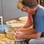 North Beach Artists Guild member Gary Ganz guides local resident Julie Pope as she learns how to make a bowl on the potter&rsquo;s wheel. (Kat Bryant | The Daily World)