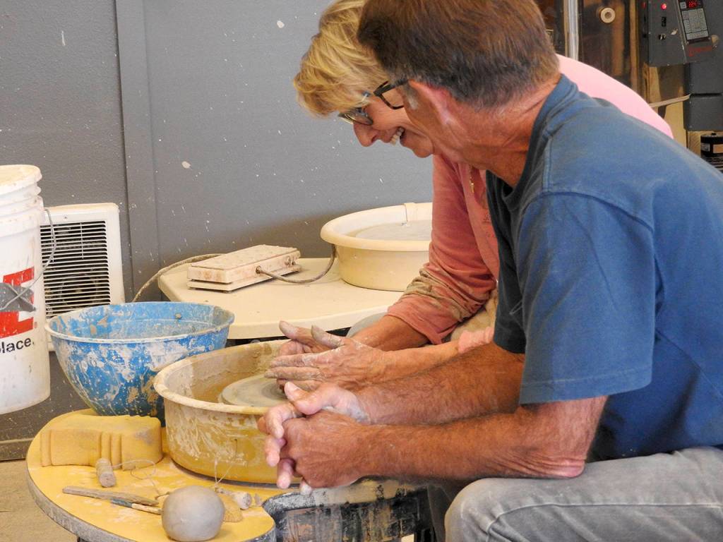 North Beach Artists Guild member Gary Ganz guides local resident Julie Pope as she learns how to make a bowl on the potter&rsquo;s wheel. (Kat Bryant | The Daily World)
