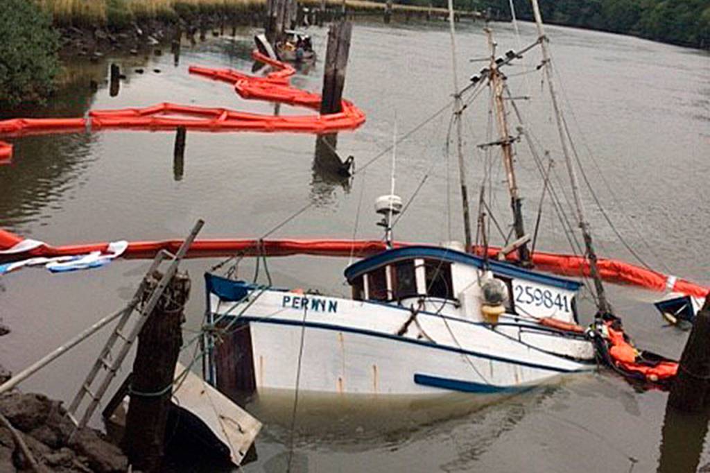 Pictured is the 42-foot commercial fishing vessel Perwyn surrounded by oil containment boom after it sank while moored on the Hoquiam River Wednesday. Global Diving and Salvage personnel placed the containment boom around the sunken vessel Wednesday night and removed an estimated 200 gallons of marine diesel from the fuel tanks Thursday morning. U.S. Coast Guard photo courtesy of Sector Columbia River Incident Management Division.
