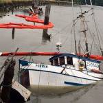Pictured is the 42-foot commercial fishing vessel Perwyn surrounded by oil containment boom after it sank while moored on the Hoquiam River Wednesday. Global Diving and Salvage personnel placed the containment boom around the sunken vessel Wednesday night and removed an estimated 200 gallons of marine diesel from the fuel tanks Thursday morning. U.S. Coast Guard photo courtesy of Sector Columbia River Incident Management Division.