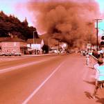 A snapshot view showing the intersection of Chehalis and Wishkah streets, and the thick clouds of acrid smoke rising from the Petrolane plant in the distance on the late afternoon of July 1, 1967. Visible on the right hand side are the Aberdeen Animal Hospital and Jack&rsquo;s Drive-In. The fire drew a sizable crowd on that warm summer Saturday. For reference, the large rooming house on the left burned down some years ago and today is the site of Cannabis 21. (Aberdeen Museum Collection)