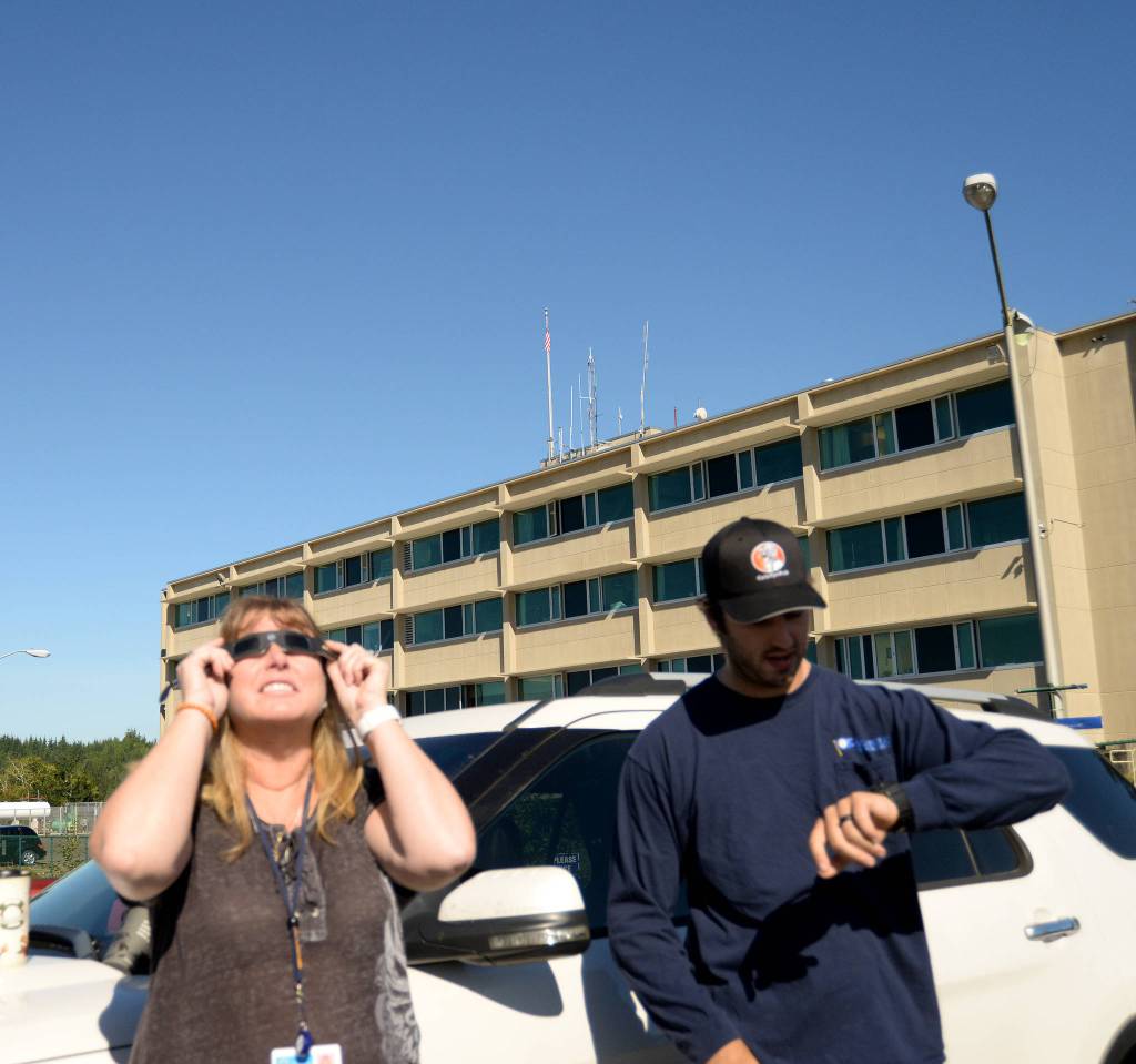 (Doug Barker | The Daily World) Laurie Wyatt of Montesano watches the eclipse from the Grays Harbor Community Hospital parking lot in Aberdeen as her son, Nolan, keeps tabs on when it would be fullest.