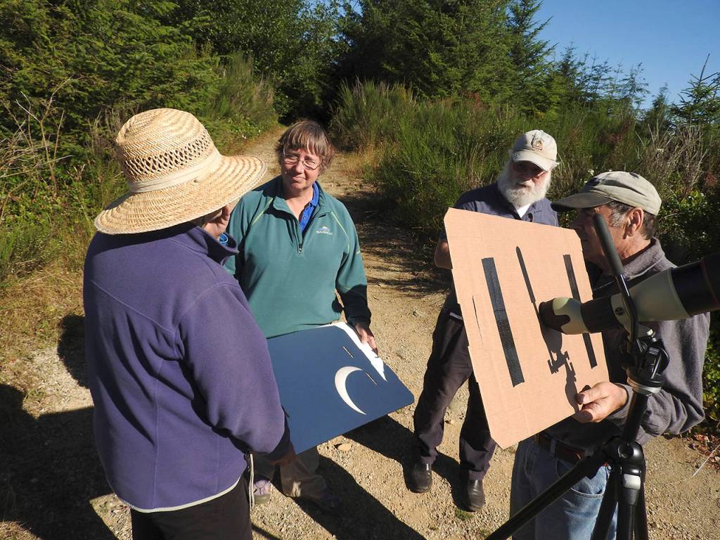(Kat Bryant | The Daily World)                                This foursome set up a pinhole viewer with a birding scope to view the eclipse on Radar Ridge.