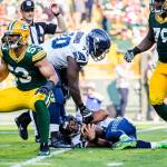 Seattle guard Rees Odhiambo helps up quarterback Russell Wilson after he is sacked for a loss of 10 yards by Green Bay Packers outside linebacker Nick Perry, left, on Sunday. (Bettina Hansen/Seattle Times)