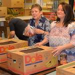 Volunteers Phyllis Granahan and Tina Miller from ASAP Business Solutions prepare Thanksgiving meals for 131 families at the Salvation Army food bank in Aberdeen. Those who preregistered for meals can pick them up on Monday. (Photo by Louis Krauss)