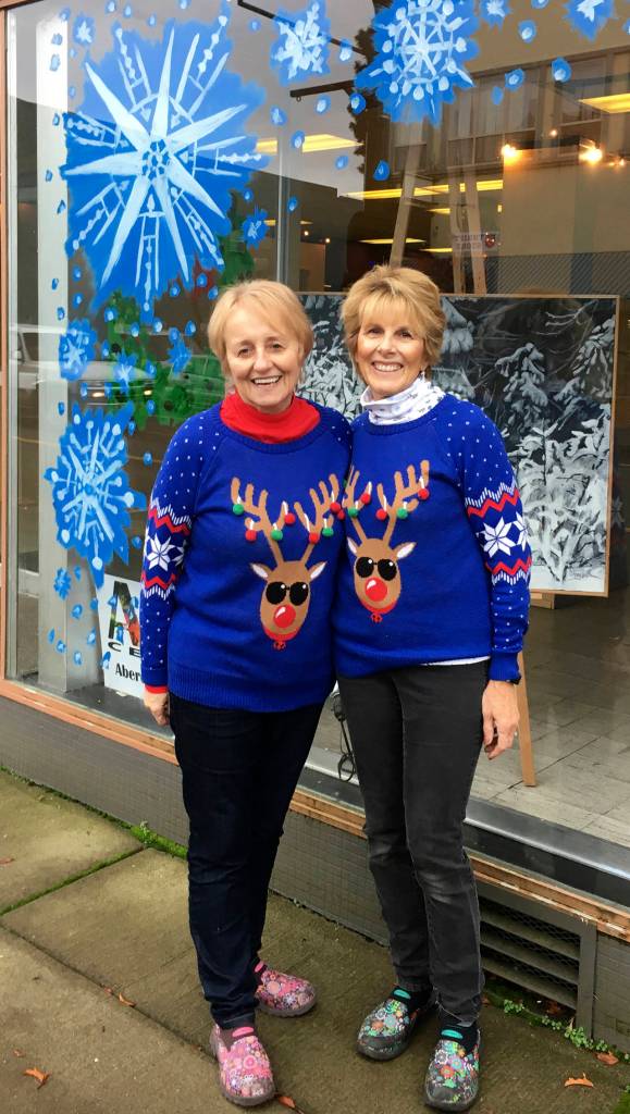 Kat Bryant | The Daily World                                Event co-organizers Bobbi McCracken, left, and Bette Worth stand outside the former site of Goldbergs Furniture Store, where local artist Douglas Orr of the Aberdeen Art Center decorated the windows in preparation for the Winterfest Market.
