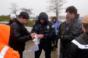 LOUIS KRAUSS | THE DAILY WORLD Sam Hutchinson (backwards black hat) shows Aberdeen Police Officer Monte Glaser the power of attorney form signed by property owner Mike Lang, allowing him to manage the property. Hutchinson decided to not tow the vehicles there after Glaser said he would have to first get a notice for eviction from the county.