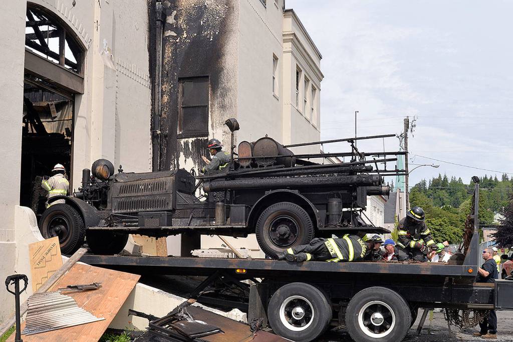 LOUIS KRAUSS | THE DAILY WORLD Aberdeen firefighters secure a burned vintage firetruck from the Aberdeen Museum of History. Because the original steering wheel was lost in the fire, firefighters attached a cutout circle to steer as they pulled it out.