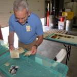 Gary Bortel, a volunteer from the Washington State Library, separates and cleans photos from the Aberdeen Museum of History in a tub of water.