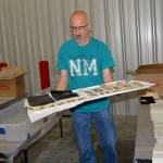 LOUIS KRAUSS | THE DAILY WORLD Volunteer Mark Vessey carries a tray of historic photos to a drying area after separating and cleaning them at a warehouse in Tumwater.