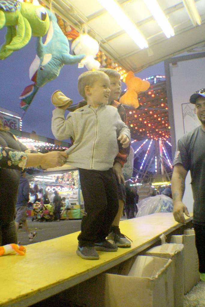 Austin Rudy, left, of McCleary winds up to throw a beanbag and try to win a prize while his friend, Coady Johnson of Aberdeen advises Friday, Aug. 10, 2018, at the Grays Harbor County Fair in Elma.