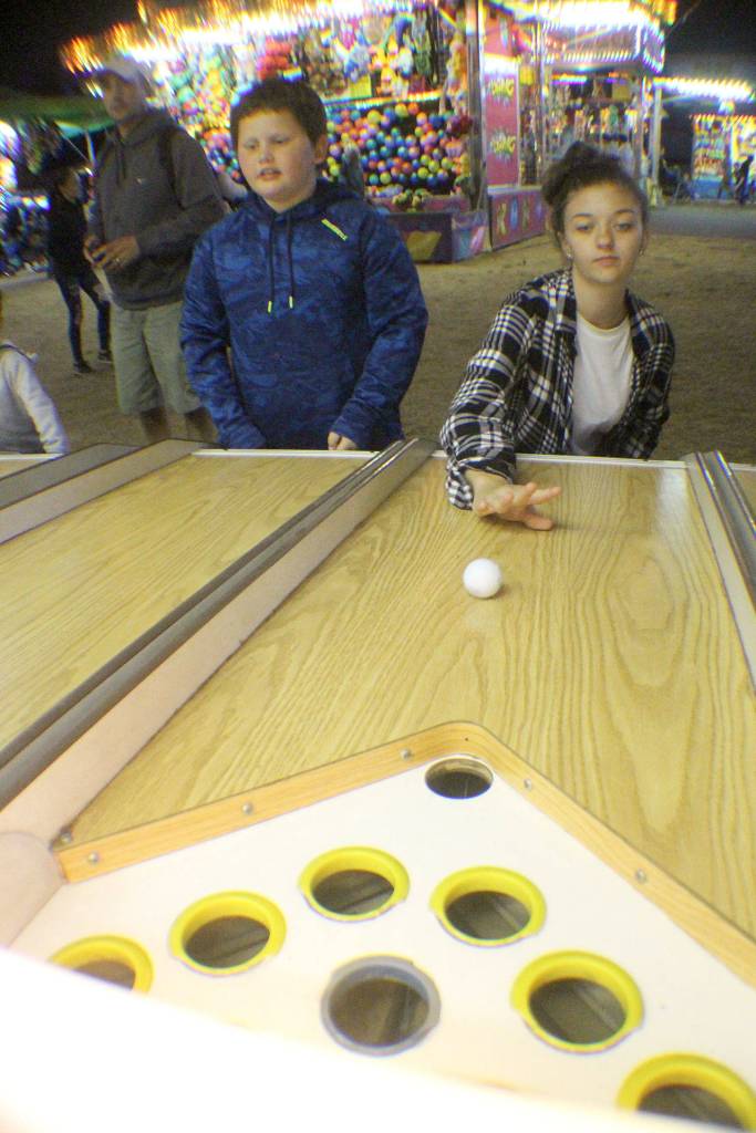 Cousins Lucas Bebich, left, of Hoquiam and Kalayah Taylor of Lacey vie for prizes by rolling balls into holes for points Friday, Aug. 10, 2018, at the Grays Harbor County Fair in Elma.
