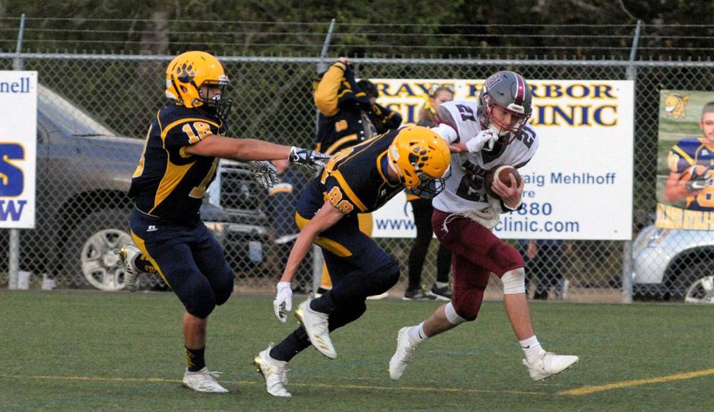 Hoquiamss Dane McMillan shakes off a tackle from Wyatt Johnson, center, in the second quarter of the Grizzlies 28-7 win on Friday at Stewart Field. (Hasani Grayson | The Daily World)
