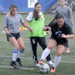 Grays Harbors Alicia Cervantes, left, and assistant coach Allie Oropeza, middle, defend against Alex Wilson during a drill at Stewart Filed on Monday. (Hasani Grayson | The Daily World)