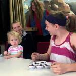 (Kat Bryant | Grays Harbor News Group) In the childrens division of the cranberry eating contest, little Dana Reynolds (held by her mom, Kat Reynolds) was given a head start, cheered on by eventual winner Kendall OHagan at right. In the background is festival organizer Tanya Lana, with more cups of berries at the ready.