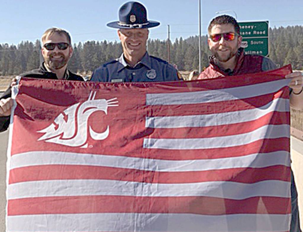 As WSU alumni Tyler Barkstrom, left, and Adam Benson stood on an overpass in Spokane waiting for the ESPN College GameDay bus to pass through on its way to Pullman, a Washington state trooper approached them. They were worried that he was going to tell them to move along  but instead, he joined them in waving the Cougar flag.