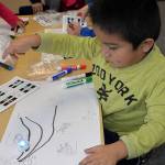 Louis Krauss | The Daily World                                A kindergarten student watches as his Ozobot robot follows the line he drew.