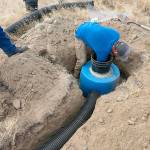 A worker installs half a 55-gallon drum in the ground at Hanford. It is intended as a nest for burrowing owls. (U.S. Department of Energy)