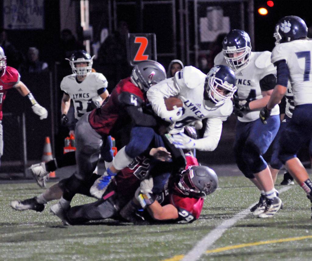 Lynden Christian receiver Zach Sipma is tackled by Hoquiams Levi Sudderth (4) and Matt Brown (29) during the Lyncs 45-6 victory in a state quarterfinal playoff game on Saturday at Stewart Field. (Ryan Sparks | Grays Harbor News Group)