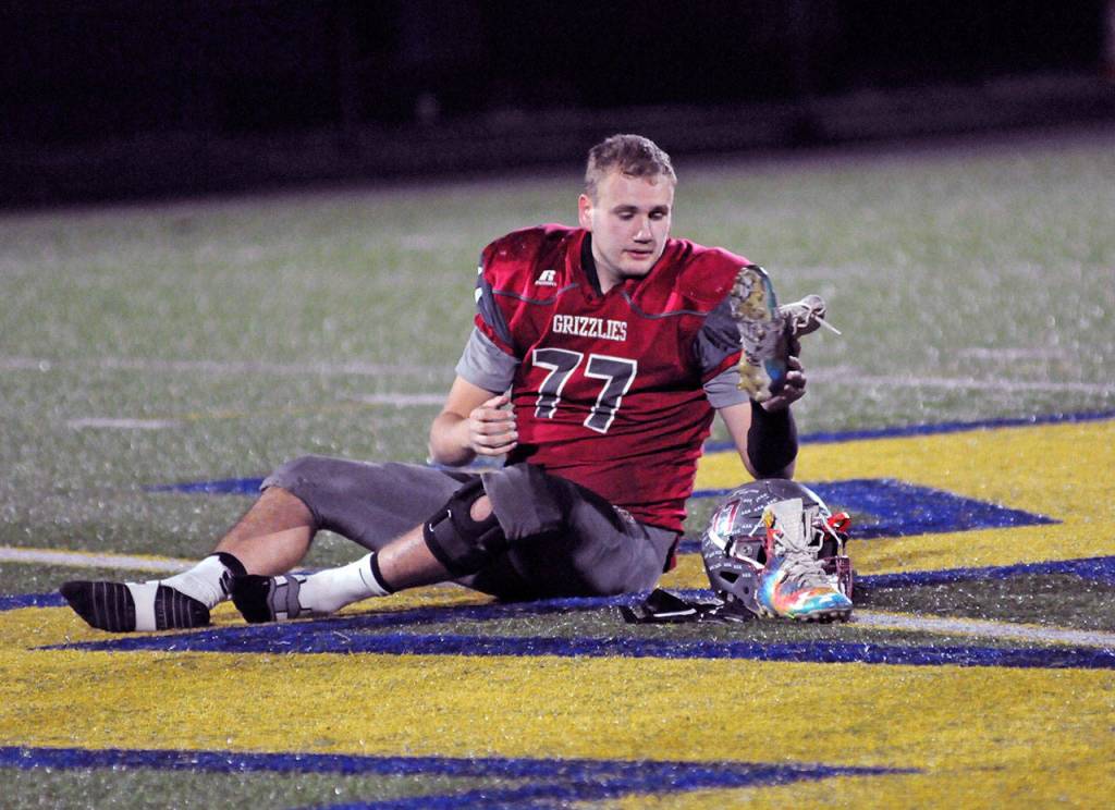 Hoquiam lineman Zack Underwood removes his helmet, gloves and cleats and leaves them at midfield, signifying the seniors last prep football game after the Grizzlies 45-6 loss to Lynden Christian in a 1A State Football Quarterfinal playoff game Saturday at Stewart Field. (Ryan Sparks | Grays Harbor News Group)