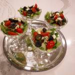 (Mitchell Chapman) Greek salad served in champagne coupes on a round silver tray.