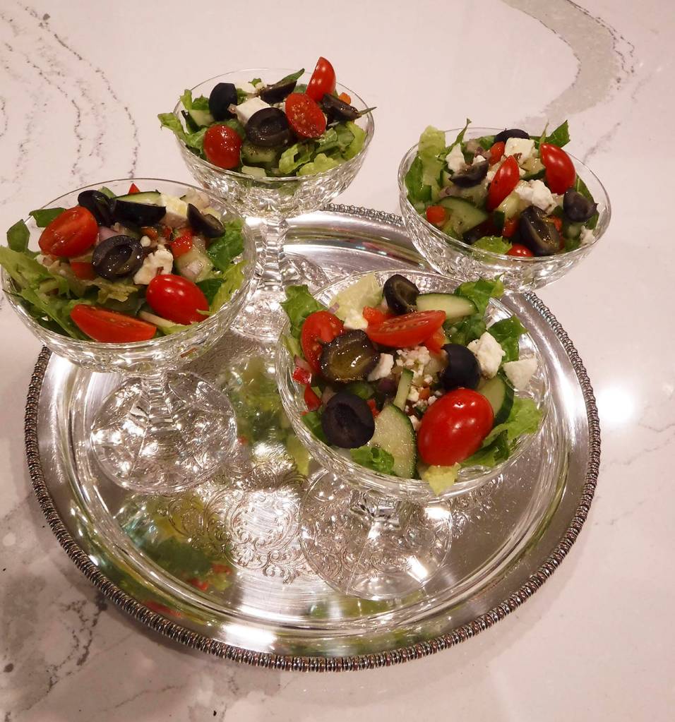 (Mitchell Chapman) Greek salad served in champagne coupes on a round silver tray.