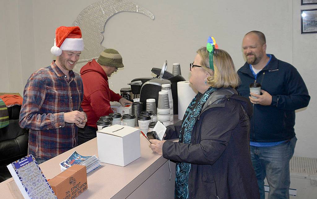 DAN HAMMOCK | GRAYS HARBOR NEWS GROUP                                Complete with Santa hat, Hoquiam Business Associations Kyle Pauley serves up cocoa for the Cocoa Stroll and maps and ballots for the Festival of Trees at the 7th Street Theatres business office Saturday evening. Folks who voted for their favorite trees in local businesses got a free commemorative 2018 Ho Ho Hoquiam ornament when they turned in their ballots.