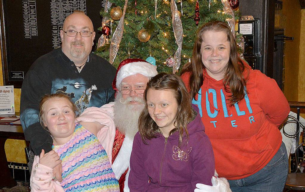 DAN HAMMOCK | GRAYS HARBOR NEWS GROUP                                Steven Beardslee and Michelle Teller flank Grays Harbor Santa inside the 7th Street Theatre Saturday. On Santas lap are Aurora Beardslee, left, and Tandra Teller. Dozens of kids told Santa what they wanted for Christmas from 5-6 p.m. at the Ho Ho Hoquiam celebration.