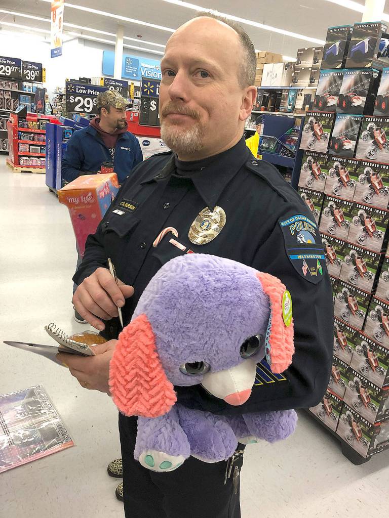 Ocean Shores Police officer Chris Iversen lugs a colorful stuffed animal through Walmart Saturday morning.
