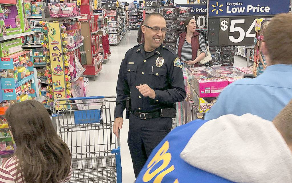 Aberdeen Police Chief Steve Shumate watches the participants of the 2018 Shop with a Cop event invade Walmart Saturday morning.