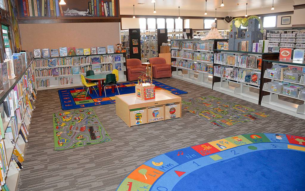 Photos by DAN HAMMOCK | GRAYS HARBOR NEWS GROUP                                 ABOVE: The childrens area of the Hoquiam Timberland Library is colorful and airy.                                RIGHT: Laurie Enholm arranges a piece of carpeting at the library on Friday morning.