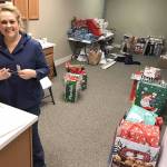 (Courtesy Kyna Wilson) Miriam Jones, owner of Picket Fence Preschool, places gift tags on packages at Hands-on-Health Chiropractic in Montesano. Savanah Jackson, background, a new employee at Hands-on-Health, spent eight hours Dec. 17 wrapping presents.