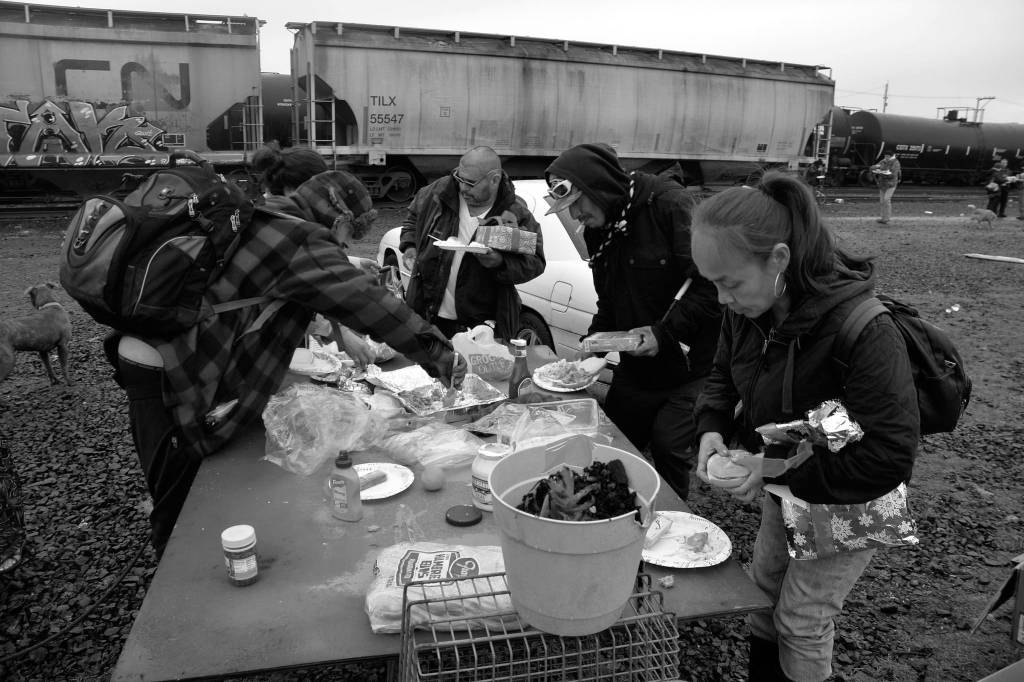 (Louis Krauss | Grays Harbor News Group) Homeless people dig into food provided as part of a holiday meal from homeless supporters on Wednesday.