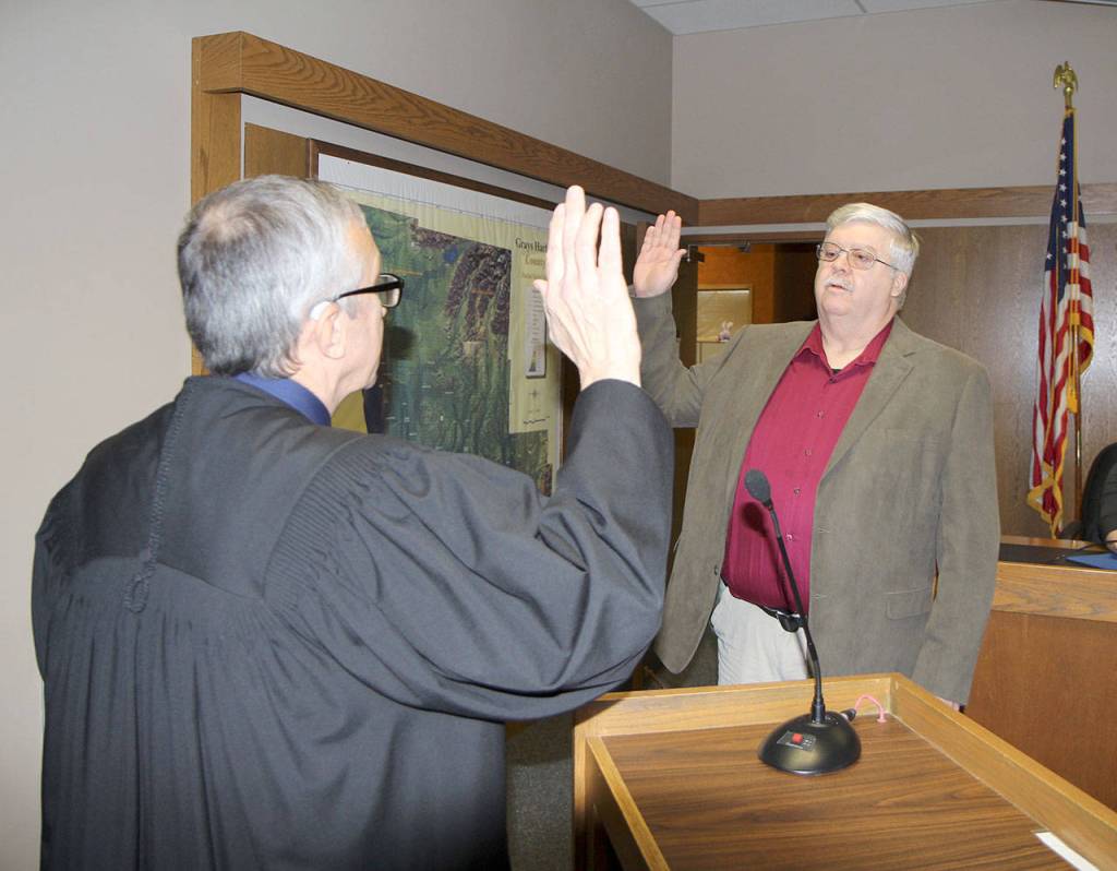 Michael Lang | Grays Harbor News Group                                Grays Harbor County Coroner Robert Kegel (right) is sworn in to office Jan. 2 by Judge David Edwards in County Commission chambers in Montesano.