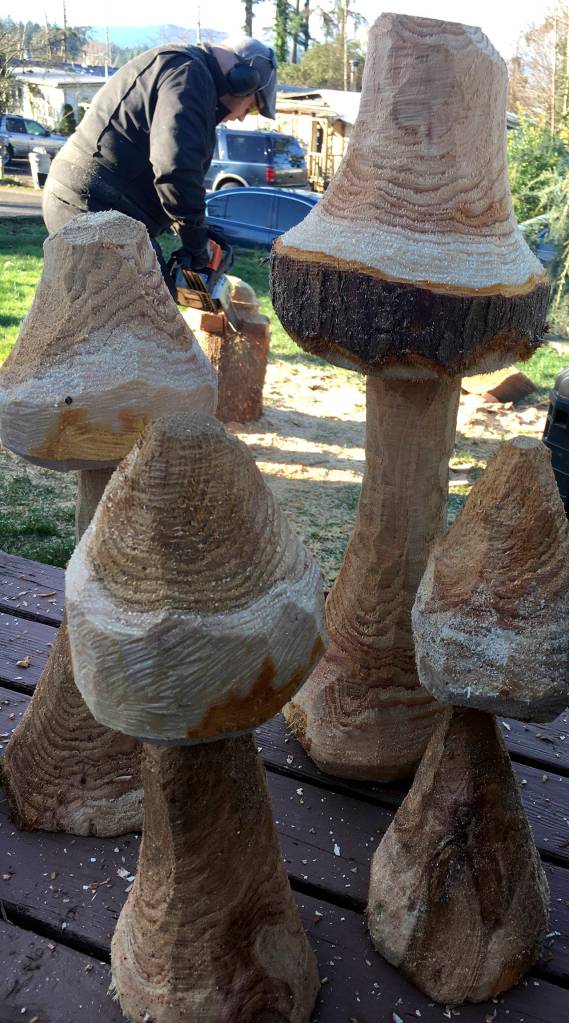 KAT BRYANT | GRAYS HARBOR NEWS GROUP Joey Felkey, a Port Orchard-based artist, carved a cluster of mushrooms from some smaller pieces of wood in the yard of Dominique Speak, who hosted the event.