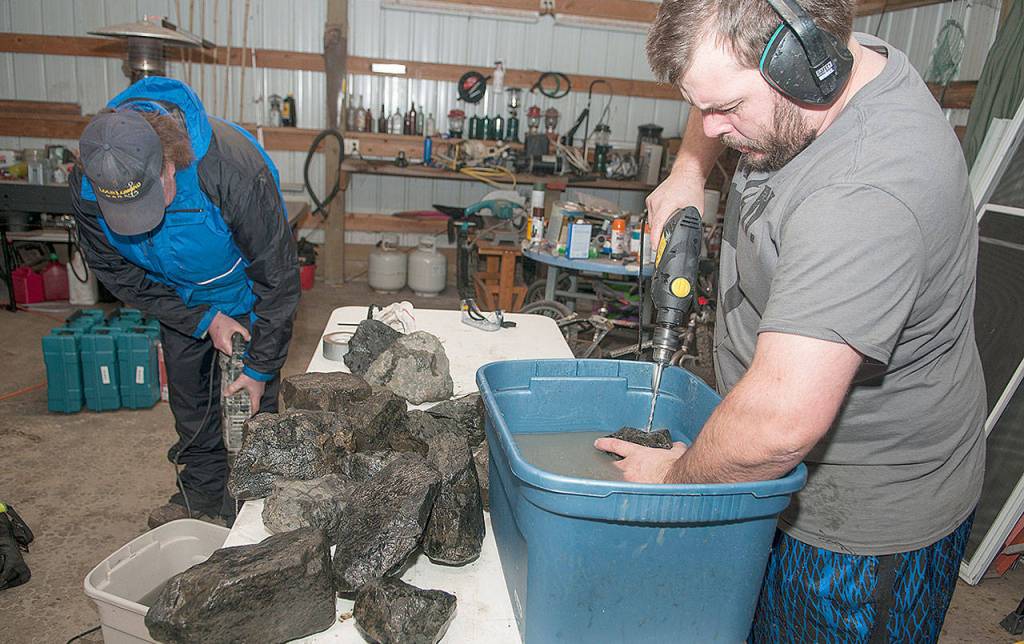 MARCY MERRILL PHOTO                                Jeremy Bartheld, right, and Brad Kirkland drill holes in rocks. The rocks were fitted with tiny transmitters and placed along the dynamic revetment on the North Cove shoreline. Their movement will be tracked by the Department of Ecology to study the effectiveness of dynamic revetment in protecting the North Cove shoreline from erosion.
