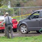 Clallam County Sheriffs Staff Sgt. John Keegan puts up crime scene tape around a property on Lower Elwha Road where a man was arrested in connection to the triple homicide. (Jesse Major/Peninsula Daily News)