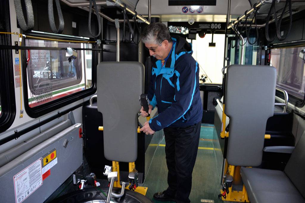 Louis Krauss | Grays Harbor News Group                                Grays Harbor Transits Ken Mehin demonstrates the new wheelchair restraints on a new bus.