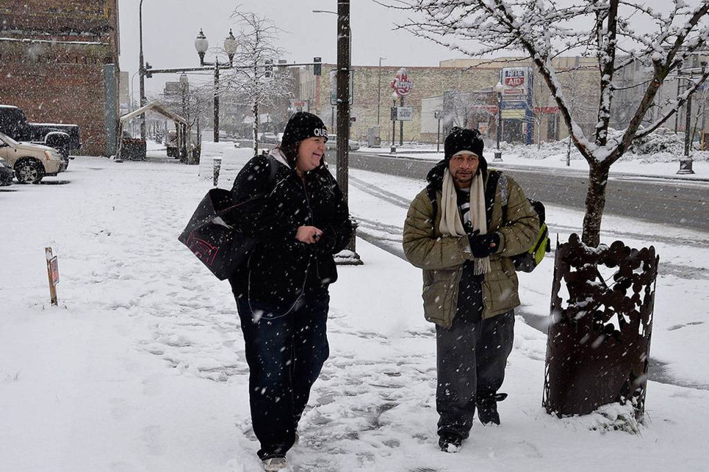(Louis Krauss | Grays Harbor News Group) Mari Oxley, left, and Viliamu Purcell walk through the snow in Aberdeen Monday morning.