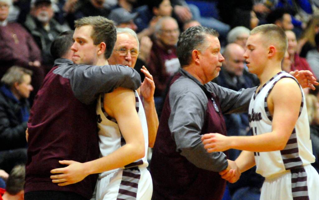 Montesano and head coach Doug Galloway, right, and assistant coach Kraig Lathorp embrace Evan Bates and Payson Parker as the Bulldogs pulled the starters from the game late in the fourth quarter. The Bulldogs lost to Cougars 74-48 and were eliminated from the 1A District IV Tournament. (Hasani Grayson | Grays Harbor News Group)