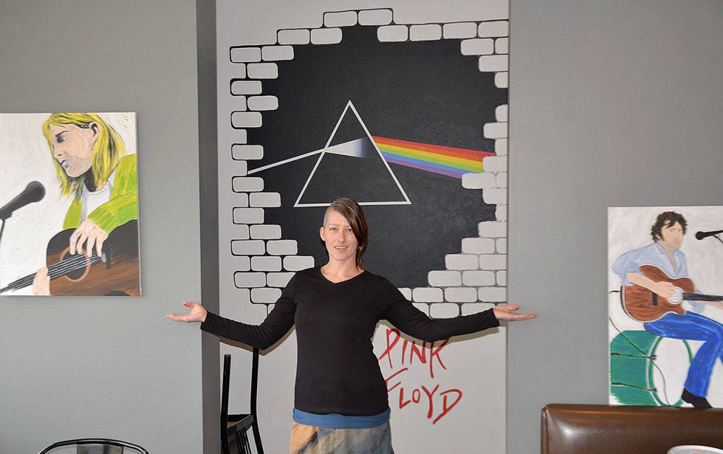 DAN HAMMOCK | GRAYS HARBOR NEWS GROUP Local artist Nina Yates with some of her works on display at the RocknBrews restaurant in Westport, due to open April 1. Behind her is a mural that combines the unmistakable art from Pink Floyds The Wall and Dark Side of the Moon albums. The canvases feature artists with local roots, Kurt Cobain of Nirvana and Leroy Virgil of Hellbound Glory.