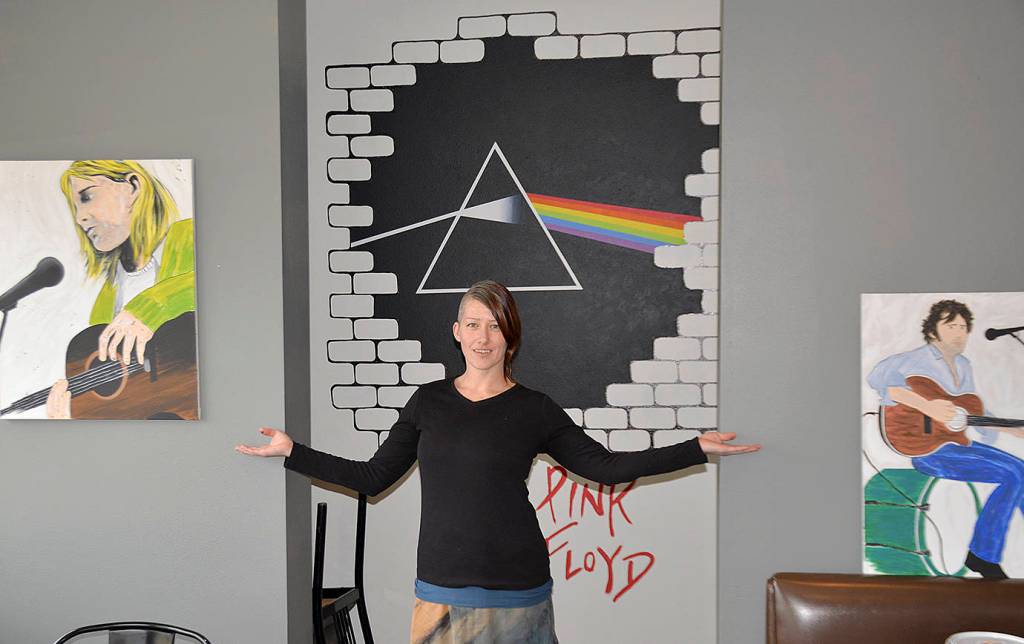 DAN HAMMOCK | GRAYS HARBOR NEWS GROUP Local artist Nina Yates with some of her works on display at the RocknBrews restaurant in Westport, due to open April 1. Behind her is a mural that combines the unmistakable art from Pink Floyds The Wall and Dark Side of the Moon albums. The canvases feature artists with local roots, Kurt Cobain of Nirvana and Leroy Virgil of Hellbound Glory.